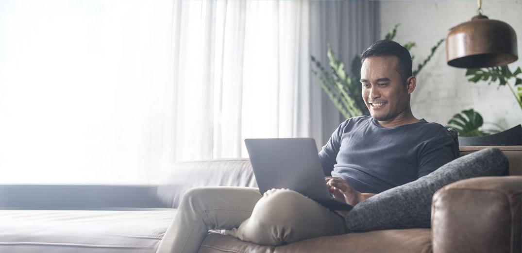 A man browses the Patelco website from his laptop at home.