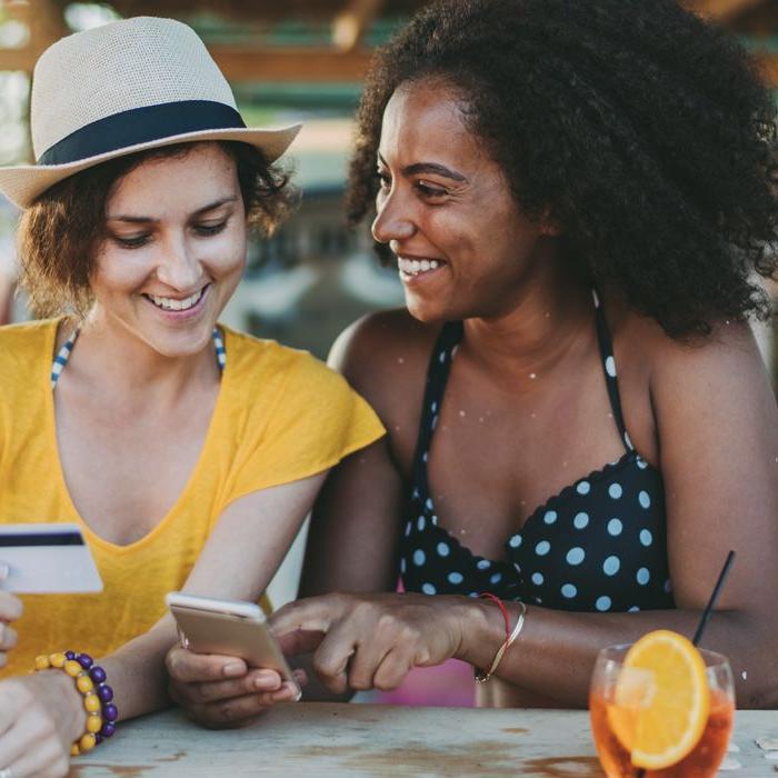 A friend transfers money from Patelco Online to her friend's account as they settle their bill at brunch.